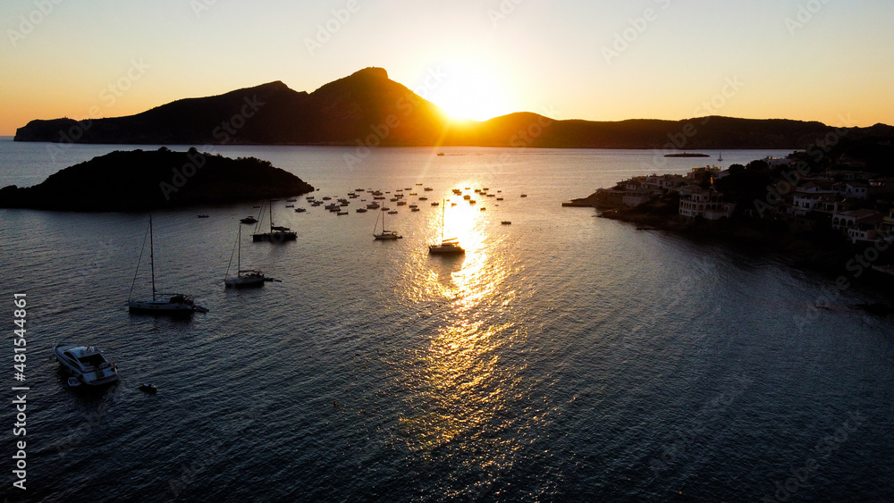 Drone shot over the ocean at sunset with boats in bay
