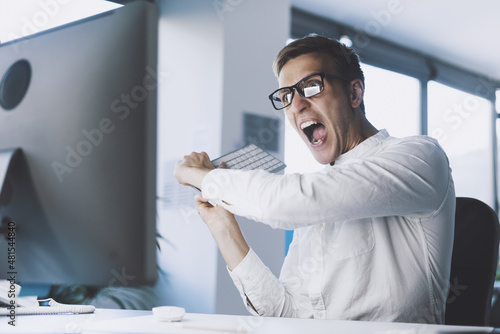 Murais de parede Insane angry businessman hitting the computer with the keyboard