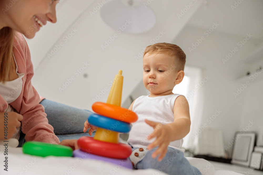 Cute little boy playing with a colorful toy near his mom Cute little boy playing with a colorful toy near his mom