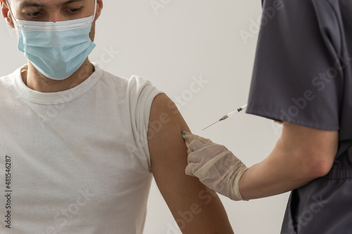 Valokuva COVID-19 vaccine injection, doctor in gloves holds syringe and makes jab to woman patient in clinic