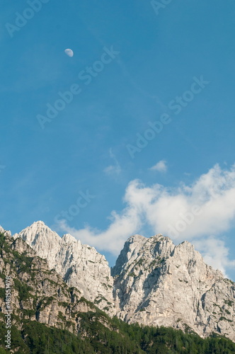 Alpine mountain range with blue sky and a moon