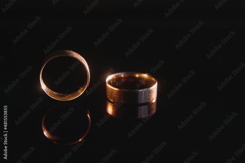 Elegant wedding rings for the bride and groom on a black background with highlights, macro, selective focus Elegant wedding rings for the bride and groom on a black background with highlights, macro, selective focus
