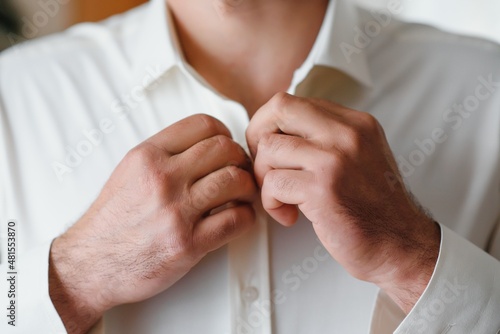 A man fastens buttons on his shirt.