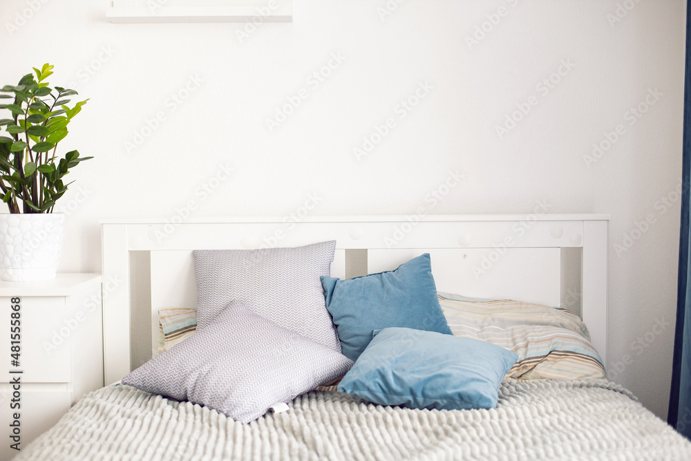minimal white interior with a double bed in the room with pillows and a green flower in pot on the bedside table minimal white interior with a double bed in the room with pillows and a green flower in pot on the bedside table
