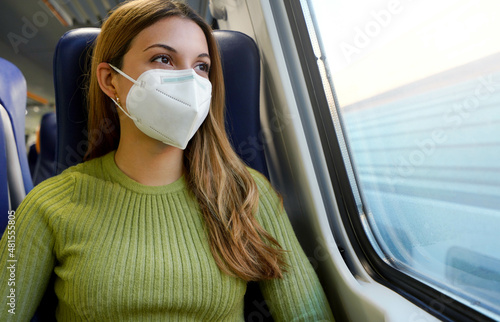 Portrait of young woman wearing protective face mask FFP2 KN95 on public transport looking through the window