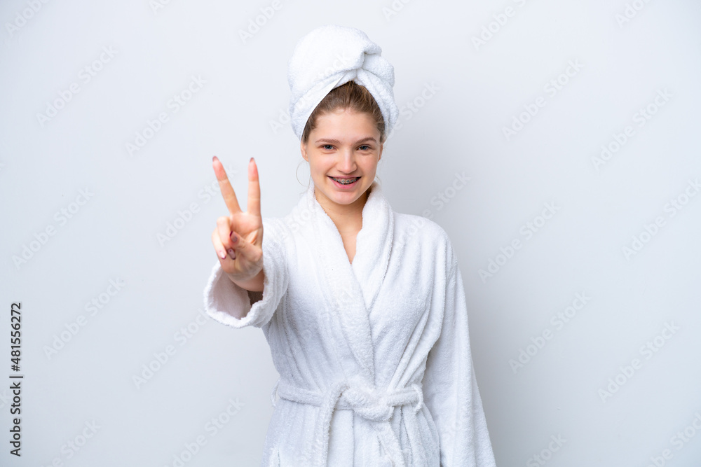 Teenager Russian girl in a bathrobe isolated on white background smiling and showing victory sign Teenager Russian girl in a bathrobe isolated on white background smiling and showing victory sign