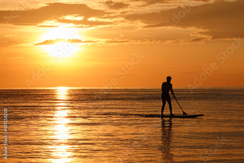 Man on paddle board and sub board floats on the ocean sea. Healthy lifestyle concept, water sports. Beautiful sunset on the beach 