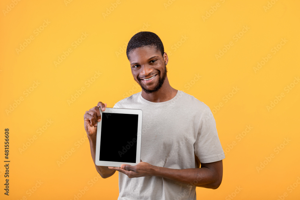 Young black guy showing digital tablet with blank screen, recommending website or mobile application, yellow background, Young black guy showing digital tablet with blank screen, recommending website or mobile application, yellow background,