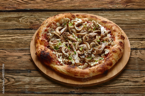 Delicious homemade pizza with mozzarella, mushrooms, beef and chicken. Dark background, selective focus.