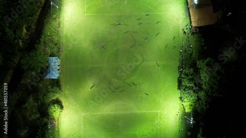 Aerial top down of two sport teams playing soccer at night in an illuminated grass field. Timelapse. photo