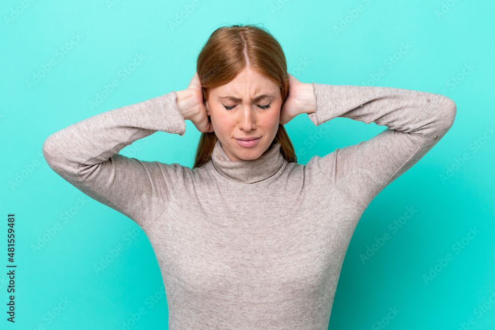 Young redhead woman isolated on blue background frustrated and covering ears Young redhead woman isolated on blue background frustrated and covering ears