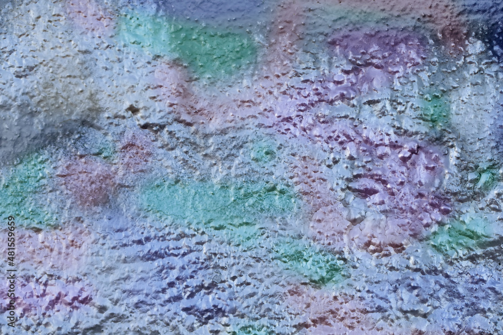 Fragments of a concrete wall painted with multi-colored metallic silver paint.