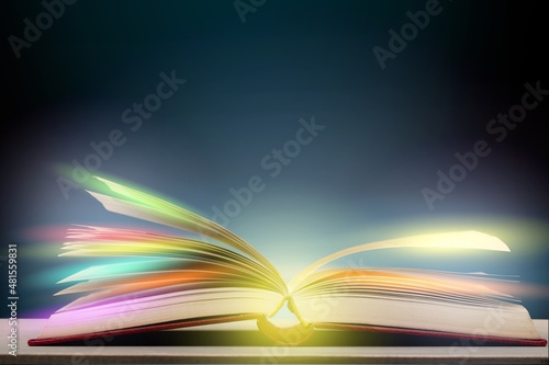 Magical image of open book over wooden table with glitter lights