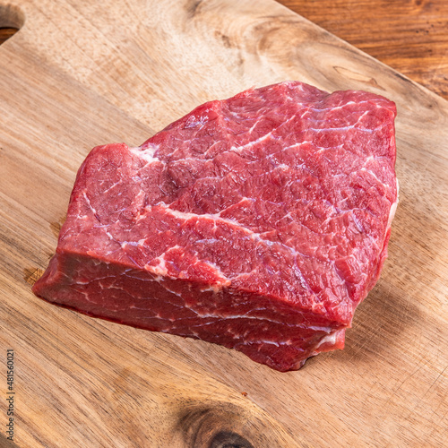 Raw piece of fresh beef on a wooden cutting board close-up