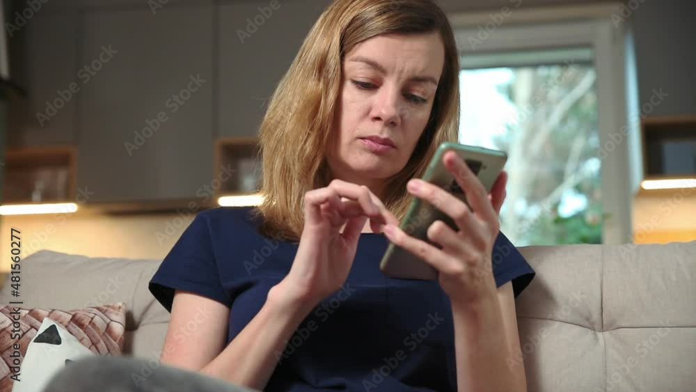Woman using smartphone for browsing social media, resting on sofa at leisure weekend. Female hand touch phone screen, surfing online news Woman using smartphone for browsing social media, resting on sofa at leisure weekend. Female hand touch phone screen, surfing online news
