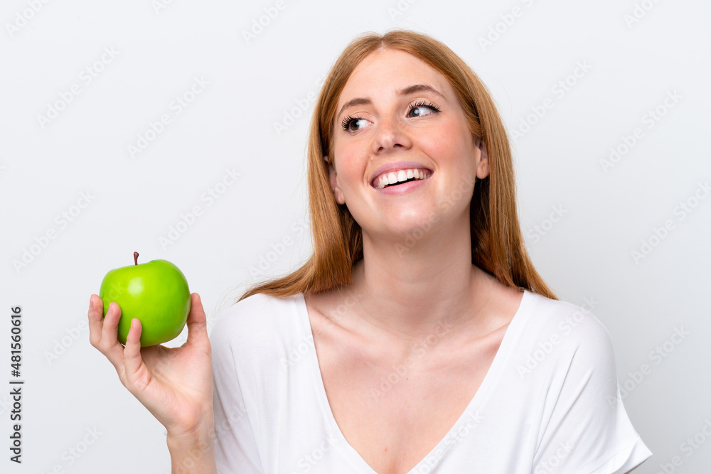 Young redhead woman isolated on white background with an apple and happy Young redhead woman isolated on white background with an apple and happy