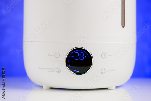 Screen modern ultrasonic ionizer humidifier on table on blue background.