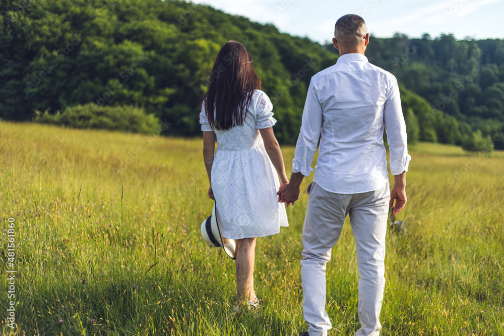 Young couple in love outdoor.Stunning sensual outdoor portrait of young stylish fashion couple posing in summer in field. Lovers walking in a field at sunset holding hands. Summer background. Young couple in love outdoor.Stunning sensual outdoor portrait of young stylish fashion couple posing in summer in field. Lovers walking in a field at sunset holding hands. Summer background.