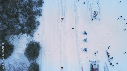 Tubing on snowy slope. Joyful Child comes down the snowy slope on a tire camera - tube: aerial reveal tilt up shot. Childrens Snow winter activities at the ski resort.