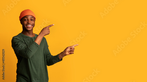 Check This. Smiling young black hispter guy pointing aside with two hands photo