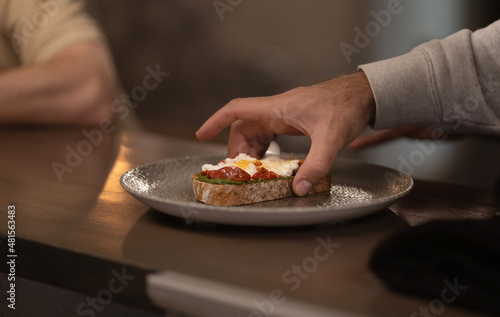A man's hand takes a sandwich from a plate in a cafe. Food concept