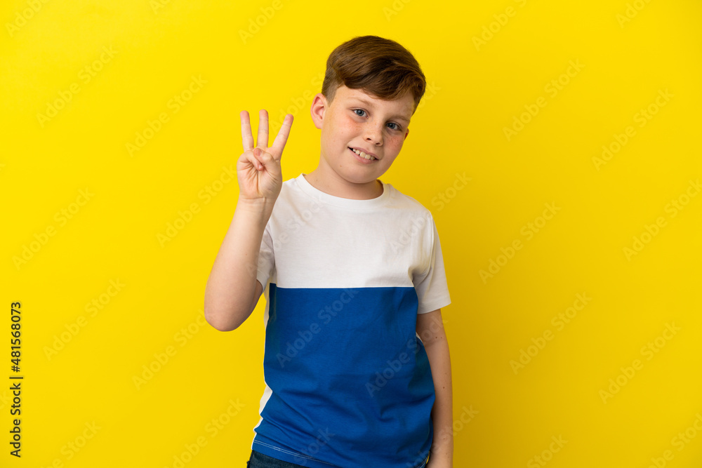 Little redhead boy isolated on yellow background happy and counting three with fingers Little redhead boy isolated on yellow background happy and counting three with fingers