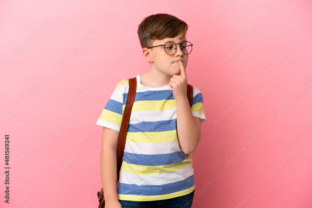 Little redhead caucasian boy isolated on pink background having doubts while looking up Little redhead caucasian boy isolated on pink background having doubts while looking up