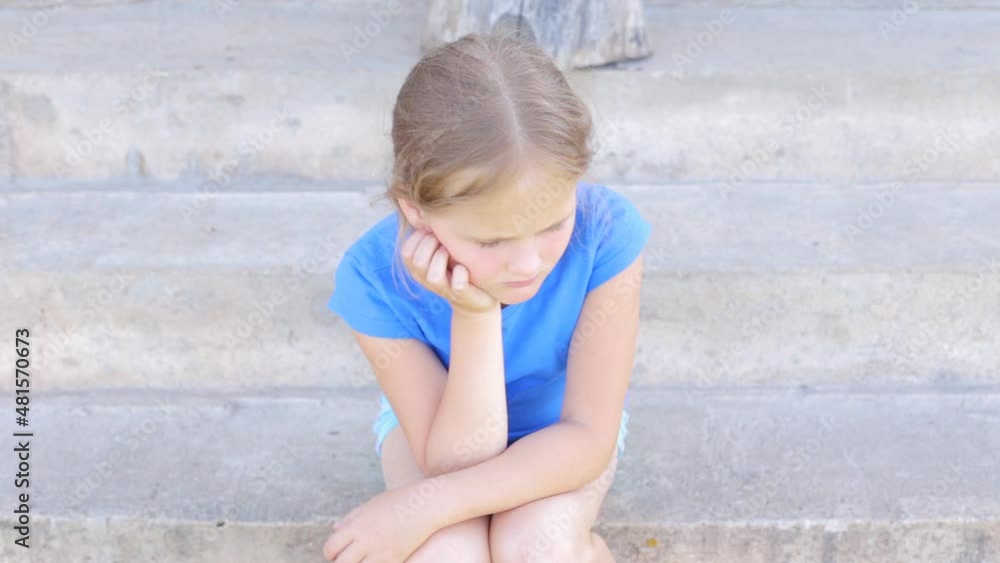A lonely child sits on concrete steps and is sad. Children's fears and experiences. A lonely child sits on concrete steps and is sad. Children's fears and experiences.