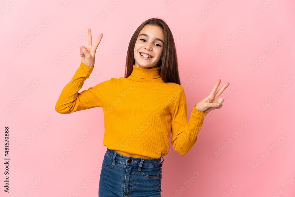 Little girl isolated on pink background showing victory sign with both hands Little girl isolated on pink background showing victory sign with both hands