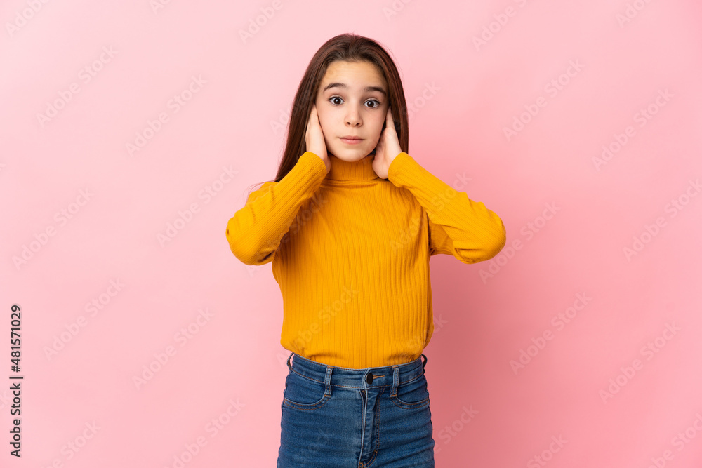 Little girl isolated on pink background frustrated and covering ears Little girl isolated on pink background frustrated and covering ears