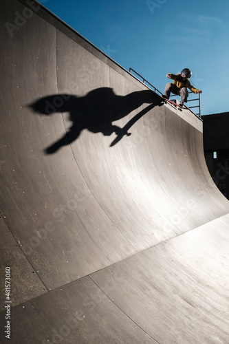 Young skater dropping on mega ramp with big shadow