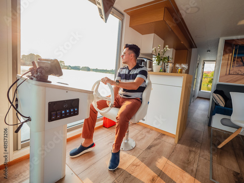 Canvas Summer vacation travel on barge boat or houseboat on a river, man by steering wh