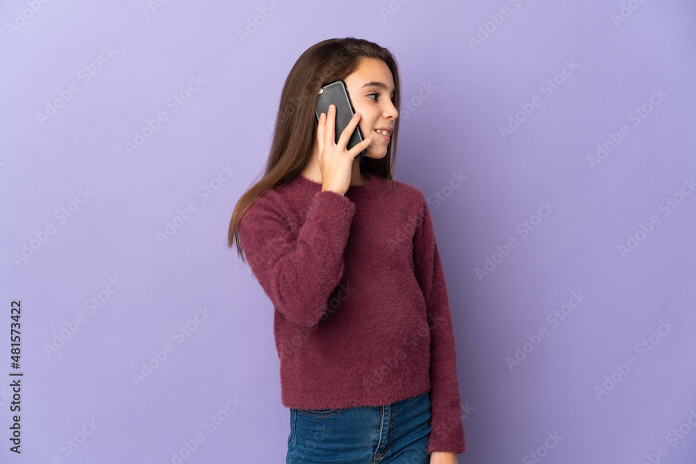 Little girl isolated on purple background keeping a conversation with the mobile phone with someone Little girl isolated on purple background keeping a conversation with the mobile phone with someone