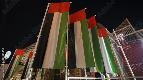 large uae flags are waving at night