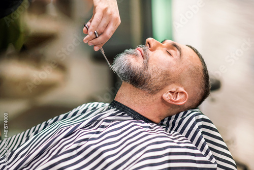 Barber using scissors to trim a clients beard