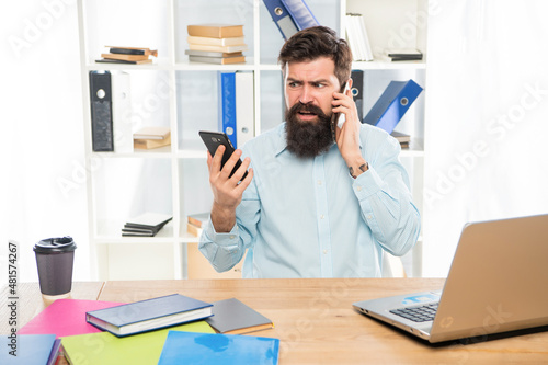 Worried lawyer talking on cellphone using smartphone at office desk, mobility