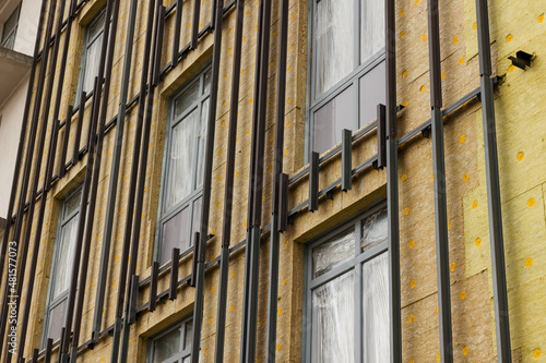 Aluminum rails for fastening a curtain wall system made of tiles on a wall with windows. Insulation and renovation of building walls with mineral wool slabs.