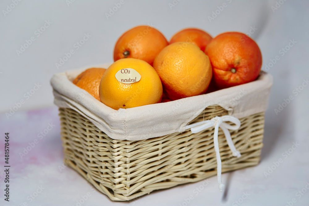CO2 neutral label on oranges. Carbon labeling. Net zero carbon, emissions free. Wicker basket with carbon neutral product label. Organic farm products from local market. CO2 neutral label on oranges. Carbon labeling. Net zero carbon, emissions free. Wicker basket with carbon neutral product label. Organic farm products from local market.