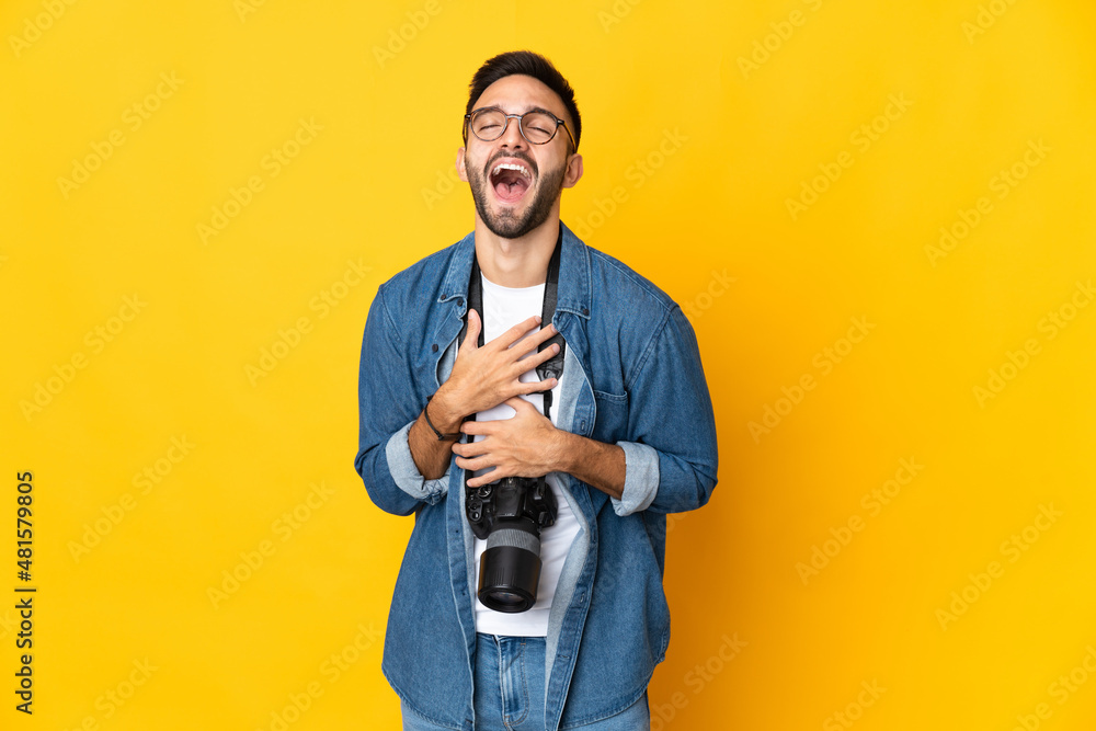Young photographer girl isolated on yellow background smiling a lot Young photographer girl isolated on yellow background smiling a lot