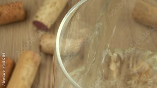 Wine is poured into a glass on the background of wine corks. photo