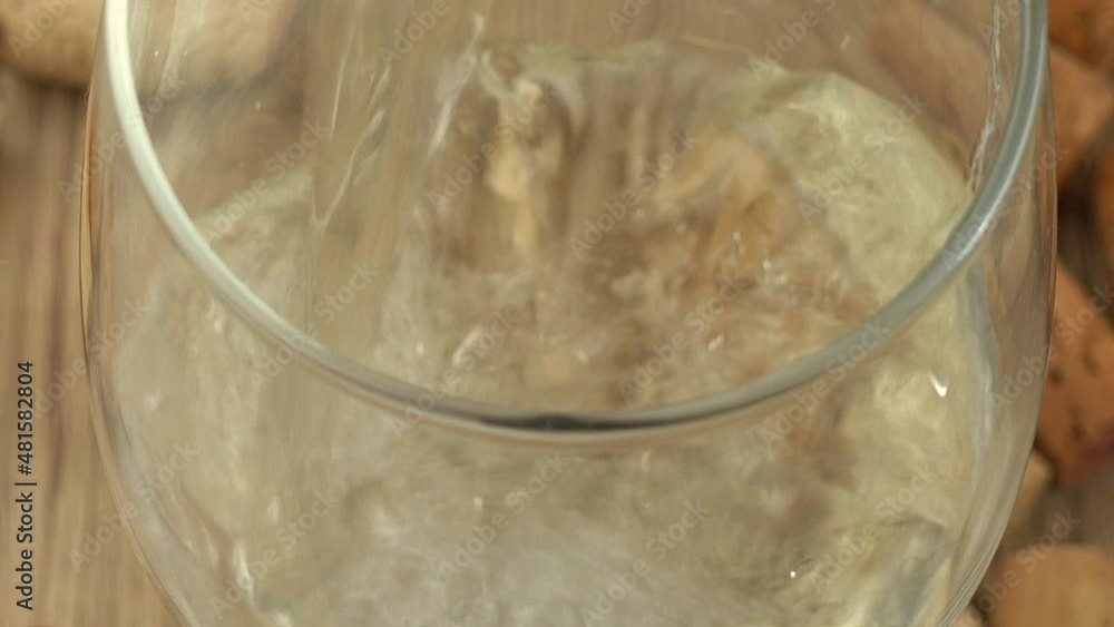 Wine is poured into a glass on the background of wine corks. Wine is poured into a glass on the background of wine corks.