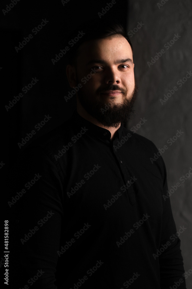 Handsome young guy with a beard in a black shirt