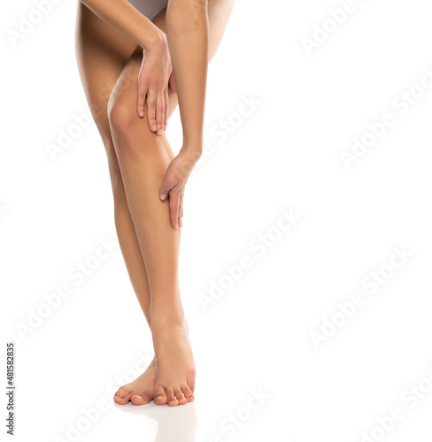 Woman applying a skin produst on her legs on a white © vladimirfloyd