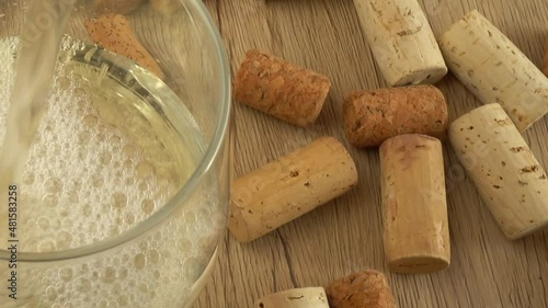 Wine is poured into a glass on the background of wine corks. photo