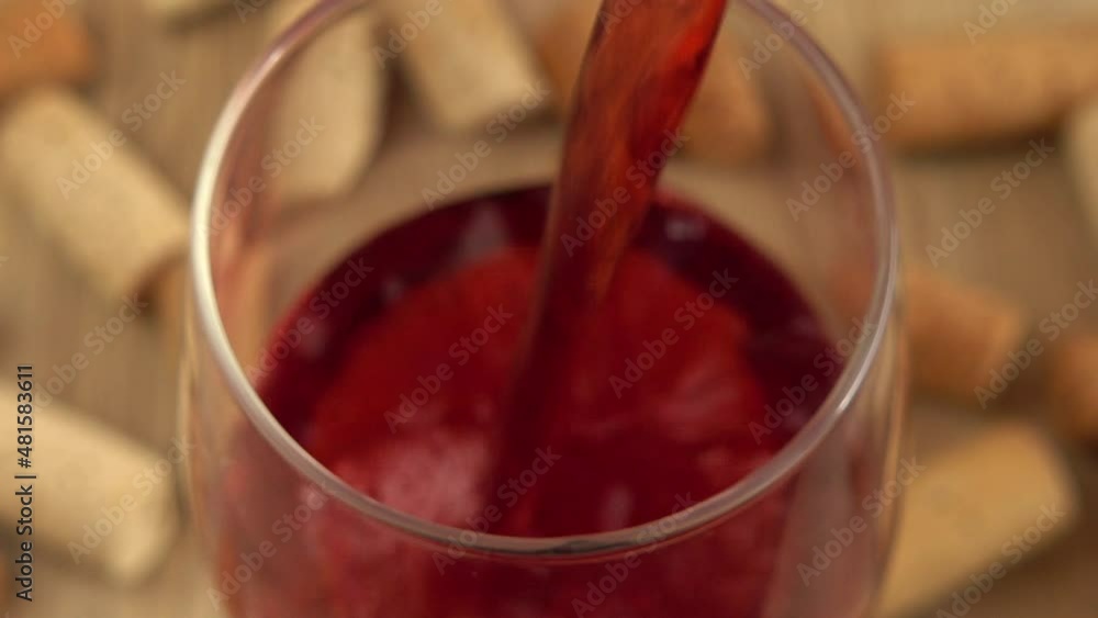 Wine is poured into a glass on the background of wine corks. Wine is poured into a glass on the background of wine corks.