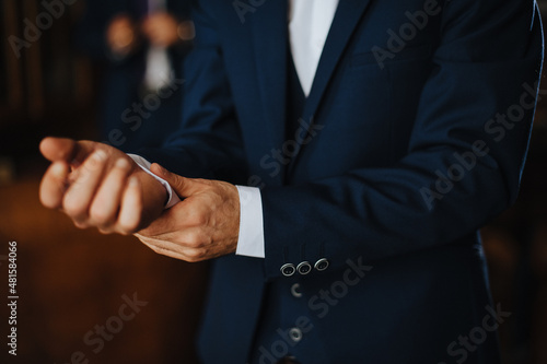 gentleman in a blue suit adjusting his sleeve