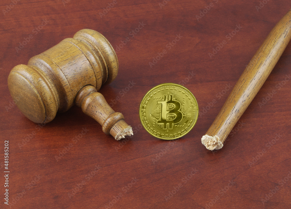 Broken wooden judge gavel and bitcoin coin close up. Broken wooden judge gavel and bitcoin coin close up.