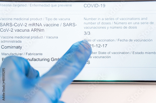 Doctor with his third dose of vaccine in his European passport against the Sars-Cov-2 virus, on this mobile phone. photo