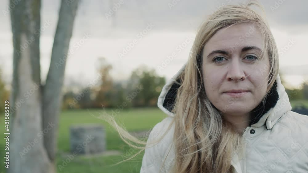 Portrait of a young pensive woman in an autumn park. Standing in a jacket with a hood on her head Portrait of a young pensive woman in an autumn park. Standing in a jacket with a hood on her head