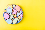 Happy Easter. Multicolored pastel easter cookies plate on a yellow background, various gingerbread glazed cookies , flat lay, view from above, blank space for greeting text, banner, flyer, coupon. 